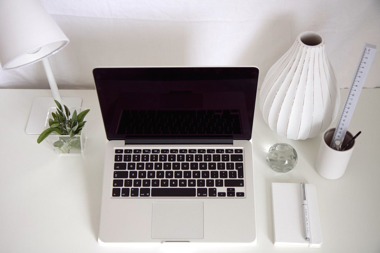 about-us Top-down view of a stylish, minimalist workspace featuring a laptop, lamp, and modern decor.